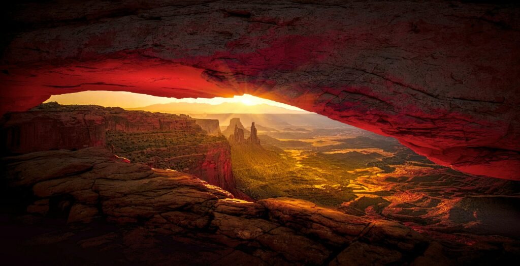 Captivating sunrise view through Mesa Arch in Canyonlands National Parks showcasing vibrant desert landscape.
