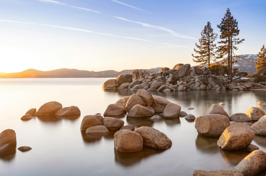pexels-photo-20763003-20763003 Tranquil scene of Lake Tahoe during sunset with rocks and pine trees along the shore.