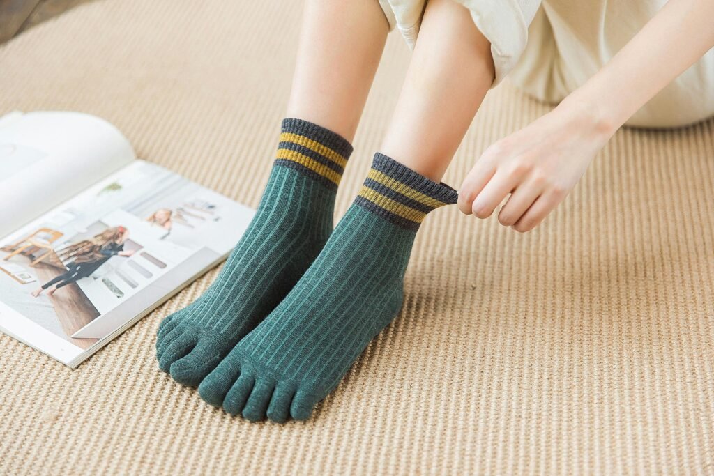 Cozy striped toe socks on a beige carpet with a magazine nearby, showing relaxed vibe.