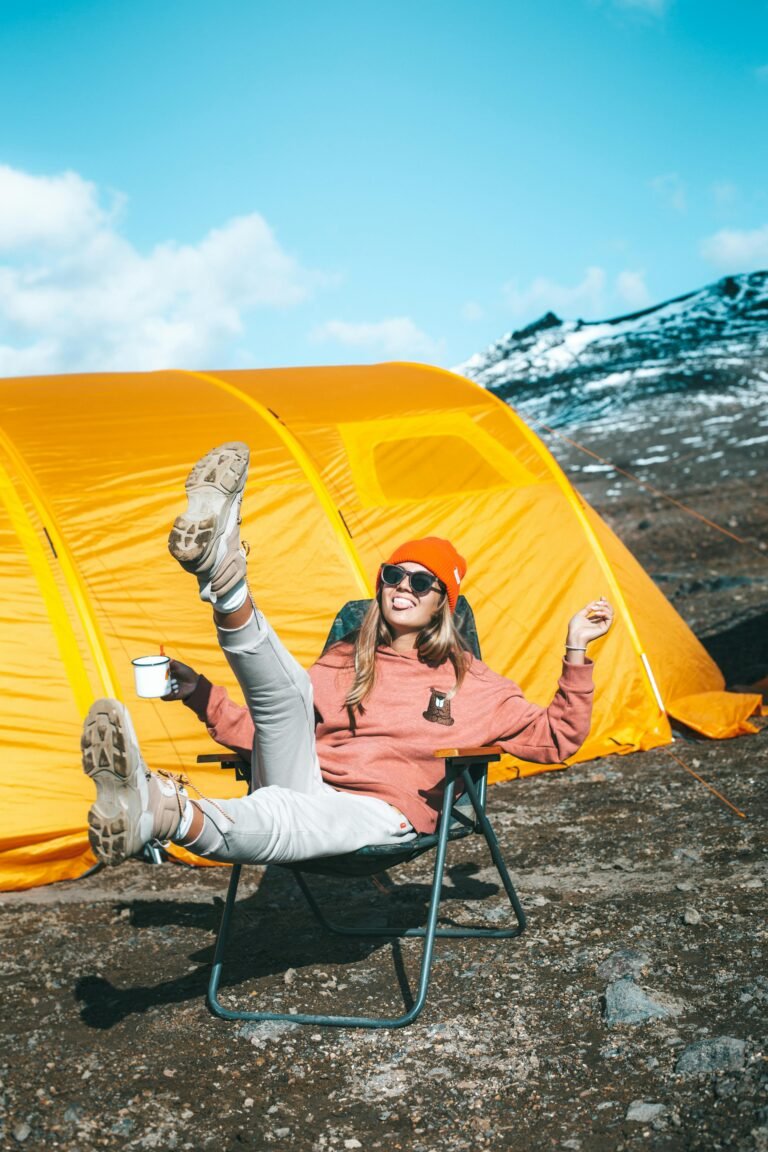 Warmly-clothed woman enjoying sunny day outdoors near a vibrant yellow tent